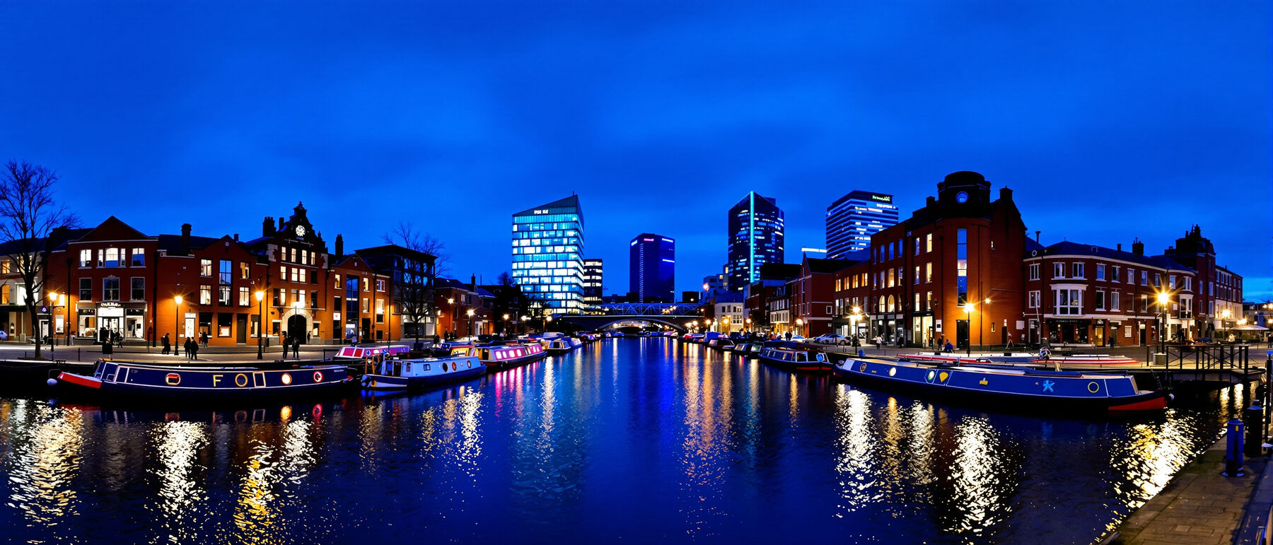 Narrowboats moored along Gas Street Basin in Birmingham at blue hour with the city lights behind